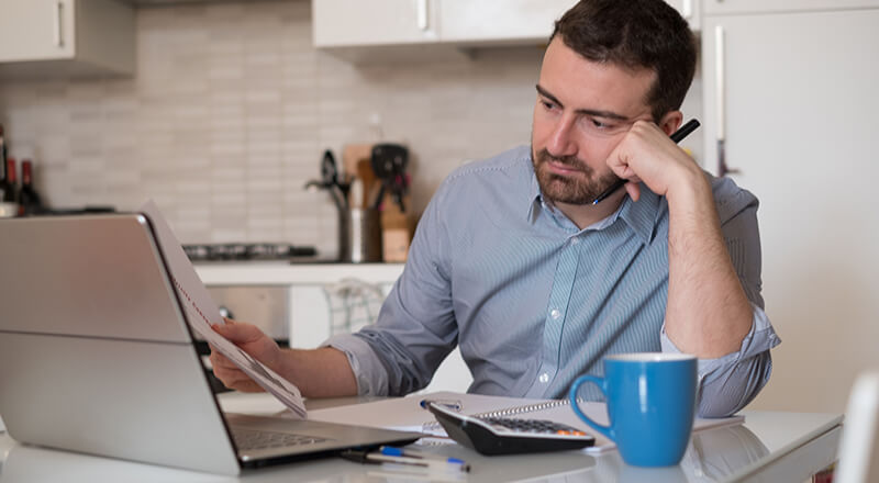 Frustrated man calculating bills and expenses.