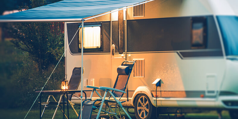Financed camper set up with chairs and a lantern at a campground.