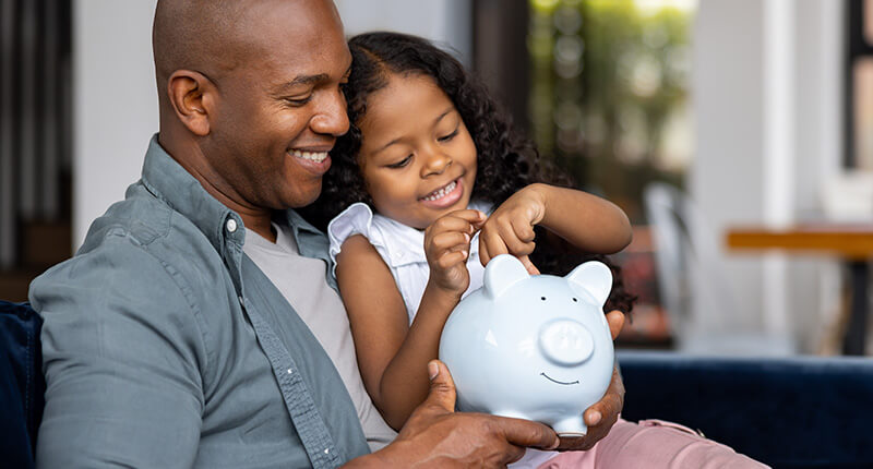 Father and daughter saving money in a piggybank