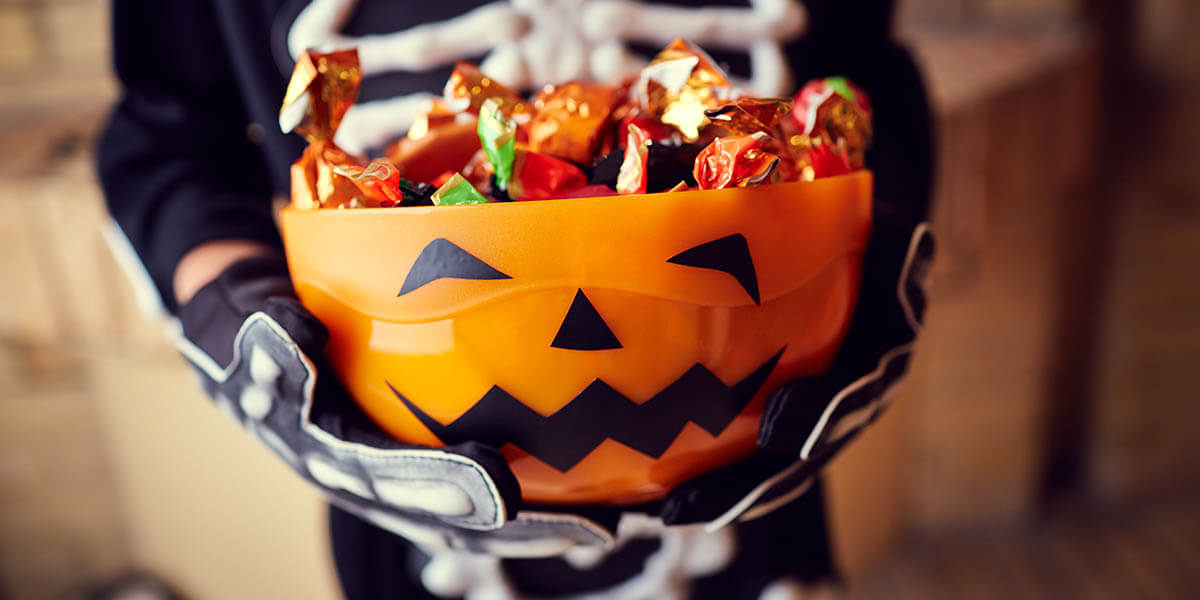 Boy in skeleton costume holding bowl full of candies