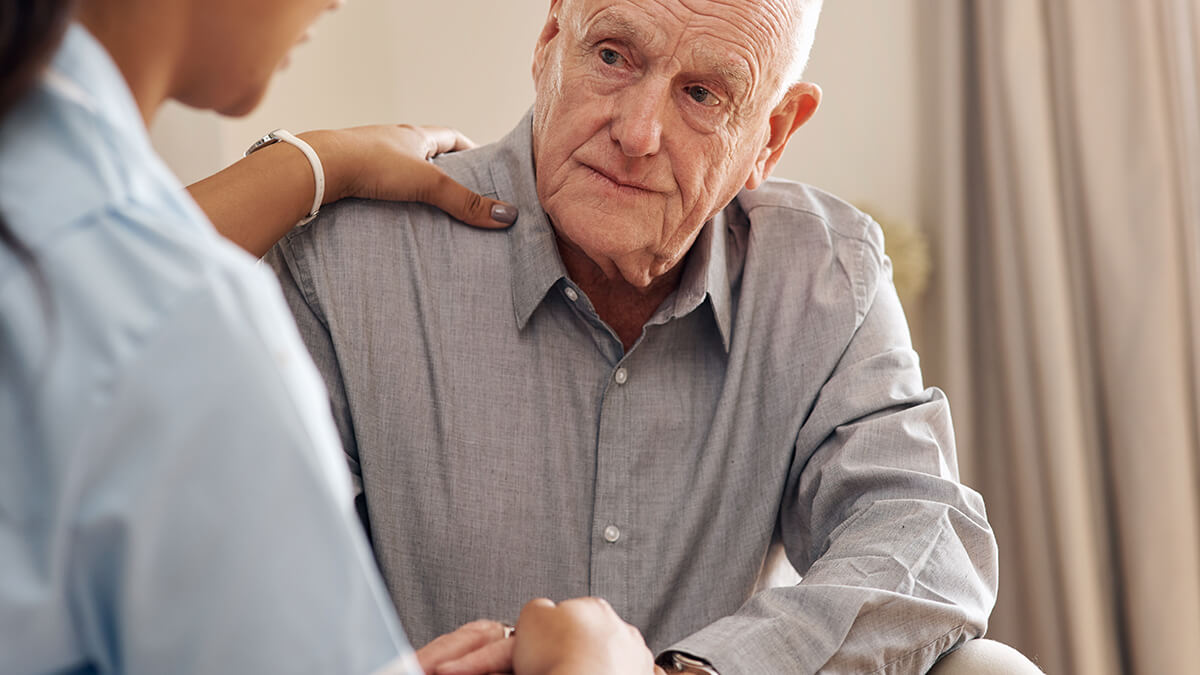 Cropped shot of an attractive young nurse sitting and comforting a senior patient