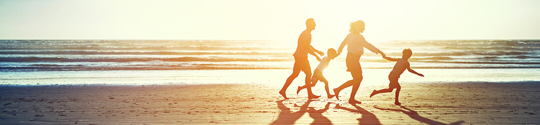 Family runs along ocean beach at sunset while on vacation paid for with a loan