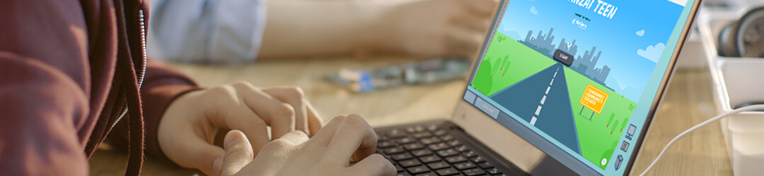 Close-up of teenager’s hands on laptop keyboard with Banzai Teen module on screen