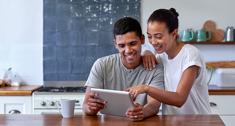 Couple in kitchen shops online for remodeling ideas, to be financed by a Home Improvement Loan