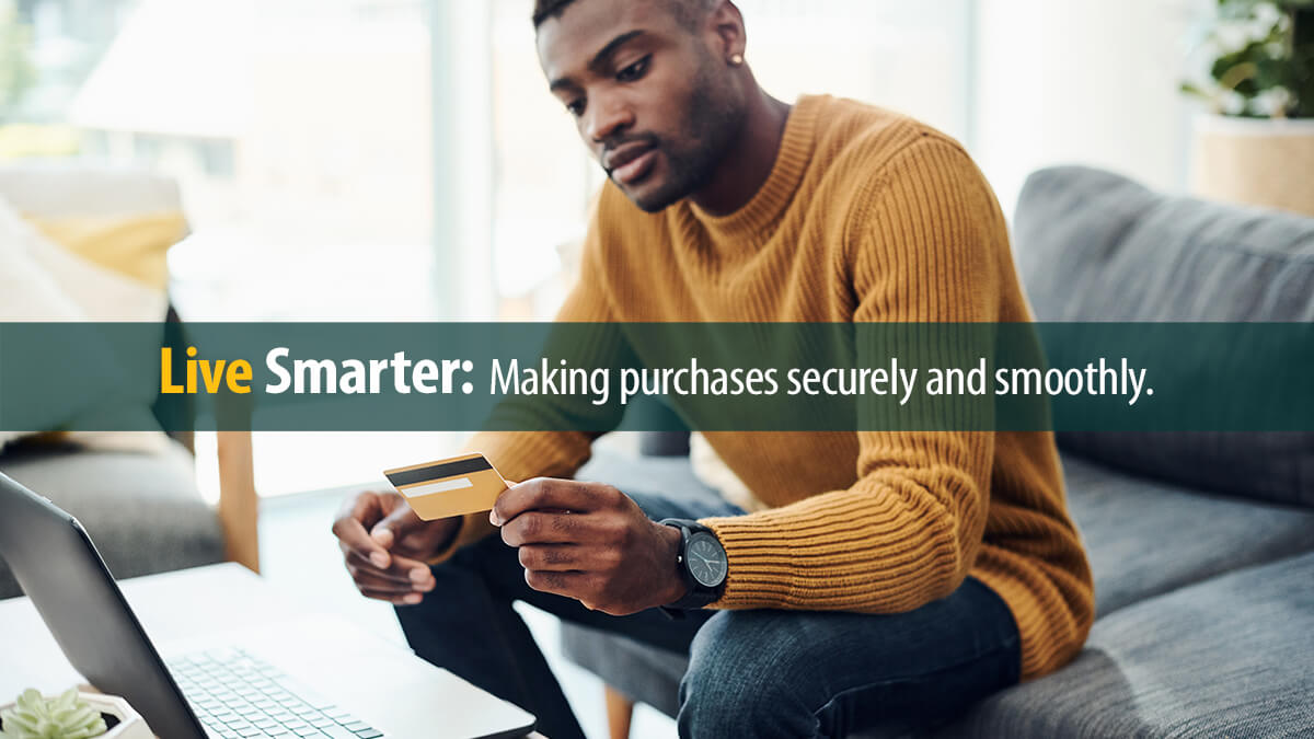 Young man using a laptop and credit card at home
